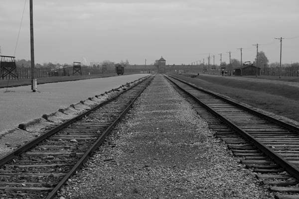 Rampe in Auschwitz-Birkenau, Ort der Selektion, mit Güterwaggon und Todestor im Hintergrund