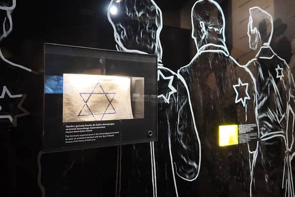 Darstellung von jüdischen Menschen im Warschauer Ghetto während der NS-Zeit, erkennbar an den Davidsternen als Symbol der Diskriminierung und Ausgrenzung.